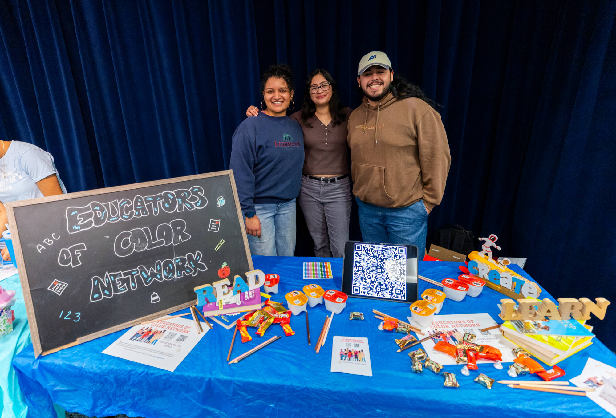 three students posing with their table for Educators of Color Network